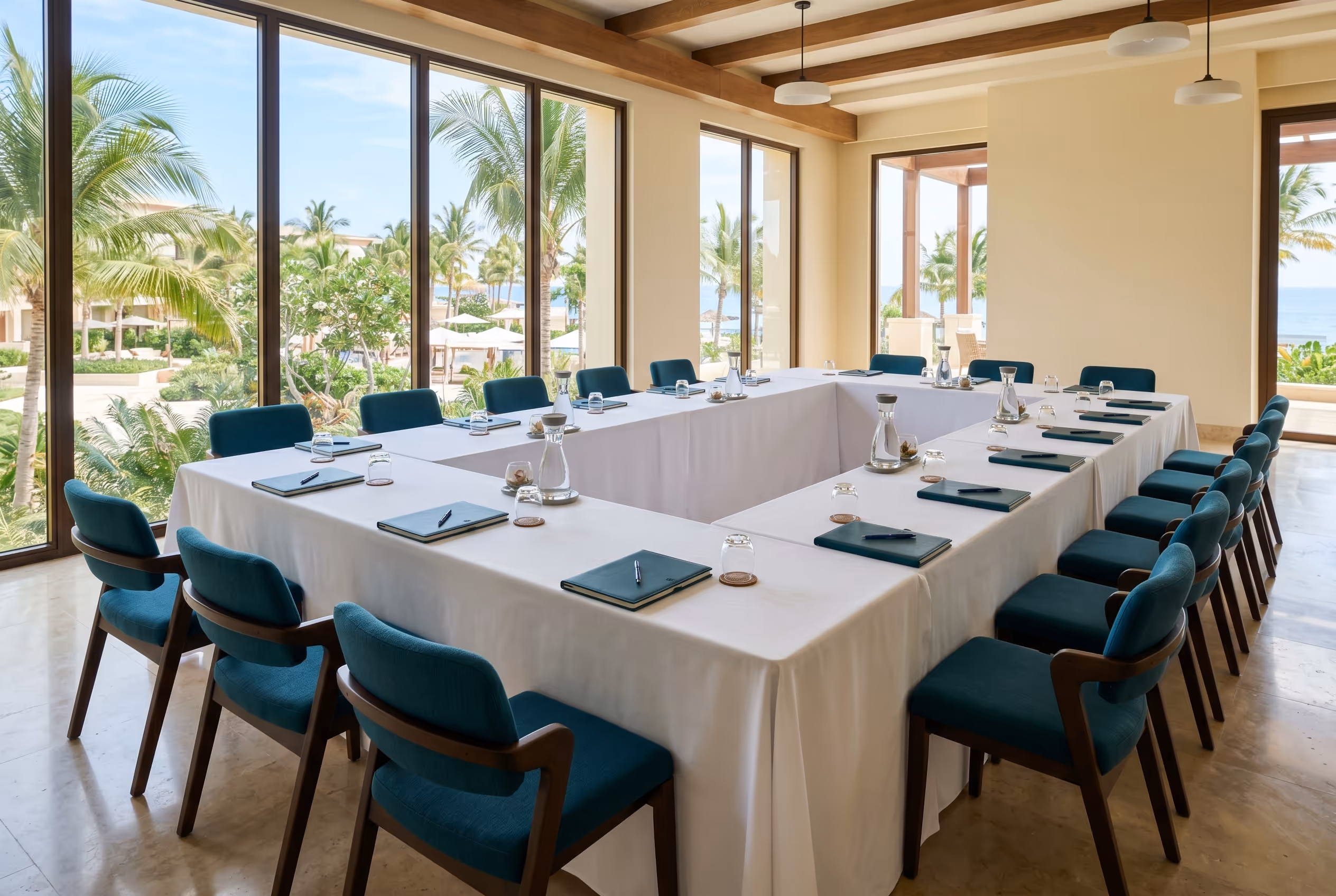 Sala para evento corporativo en Hotel Malibu con mesas en U, manteles blancos y vista a palmeras